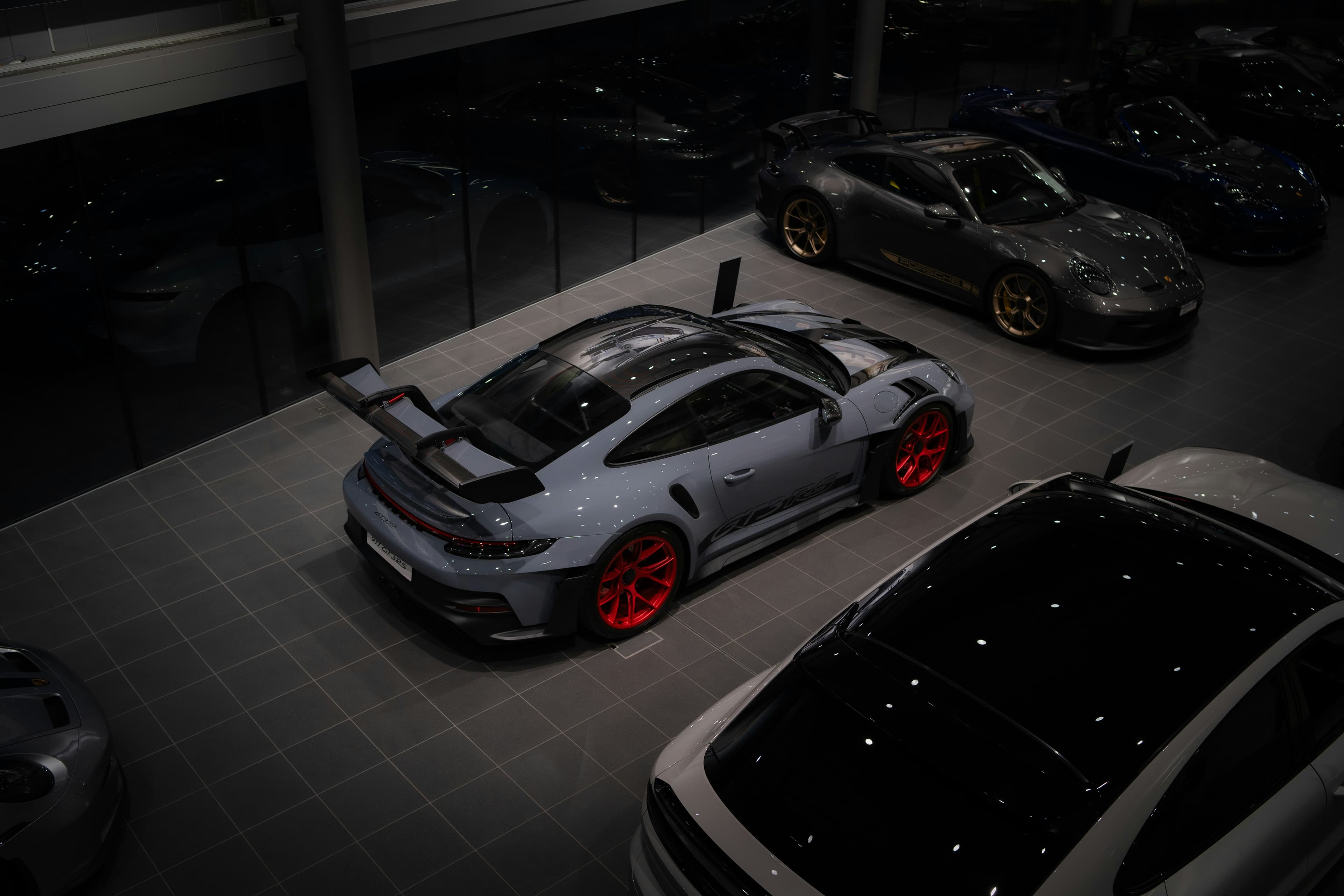 Black Porsche and Audi vehicles displayed outdoors at sunset